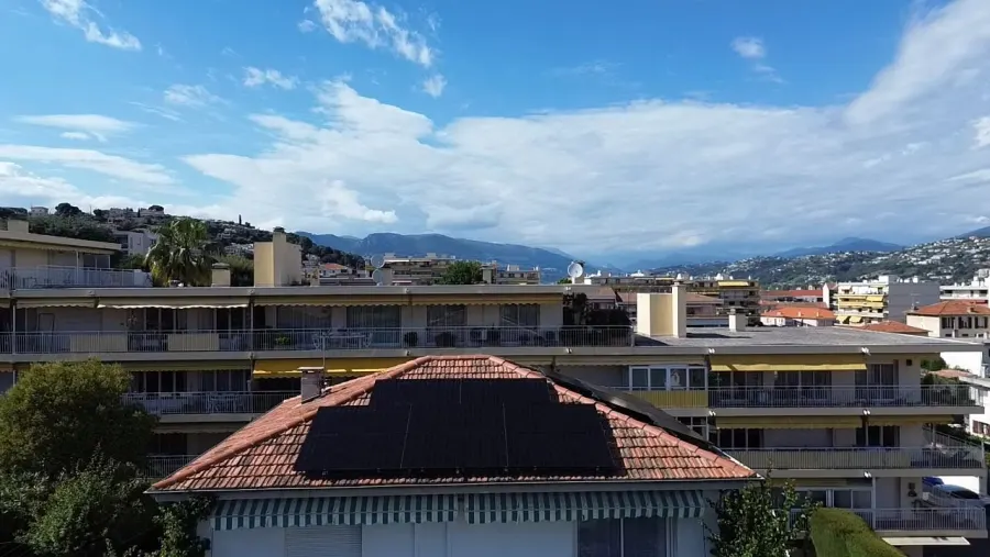 Toiture équipée de panneaux solaires à Saint-Laurent-du-Var, collines en arrière-plan