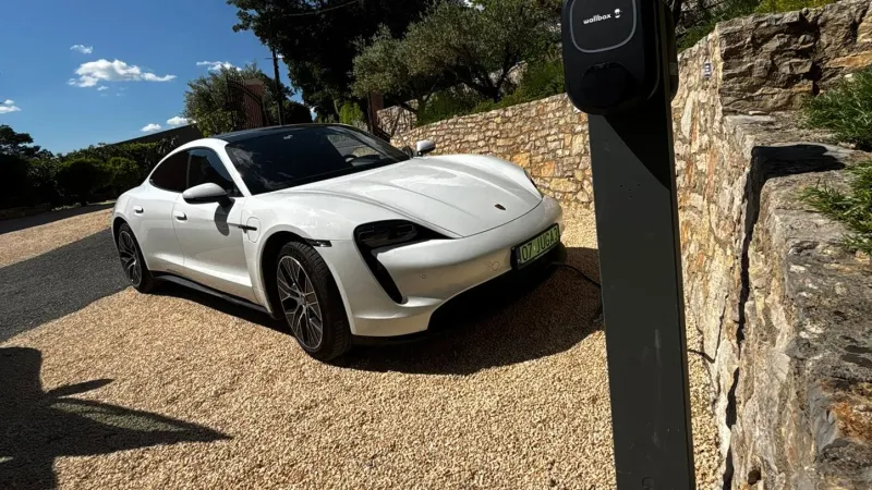 Wallbox sur potelet, véhicule électrique en charge devant un mur en pierre